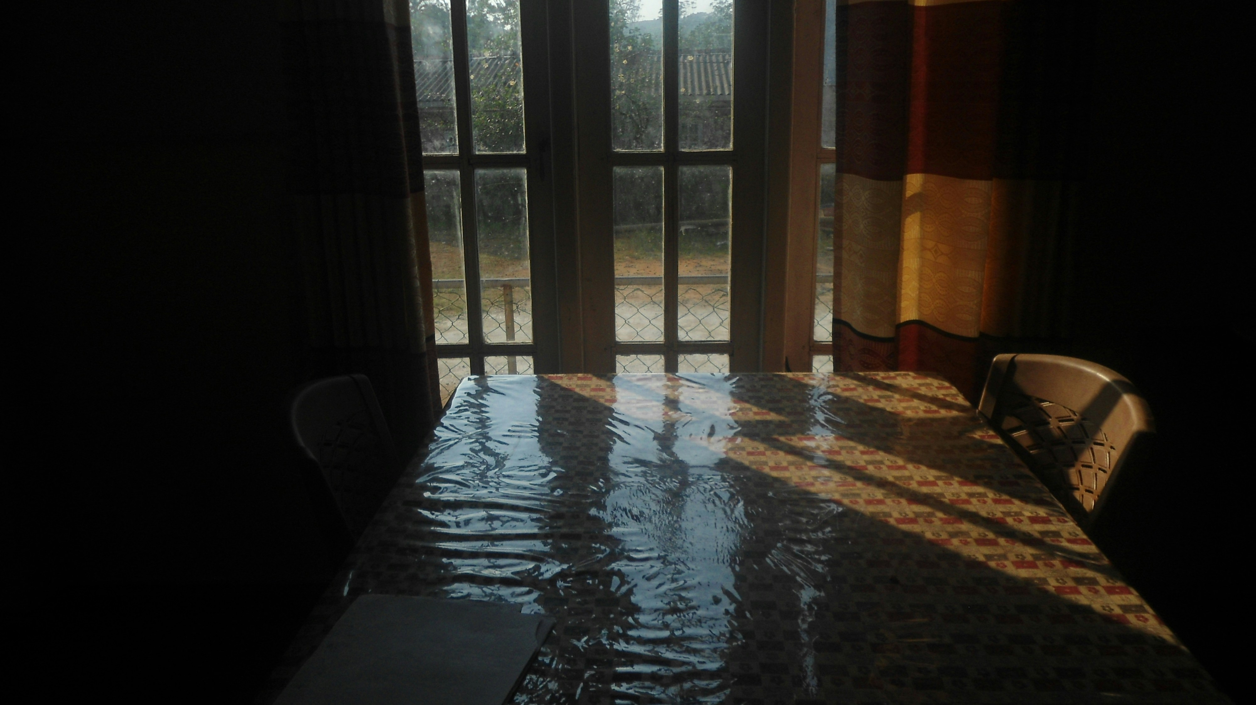 Sunlight streaming through window onto a table with a plastic cover