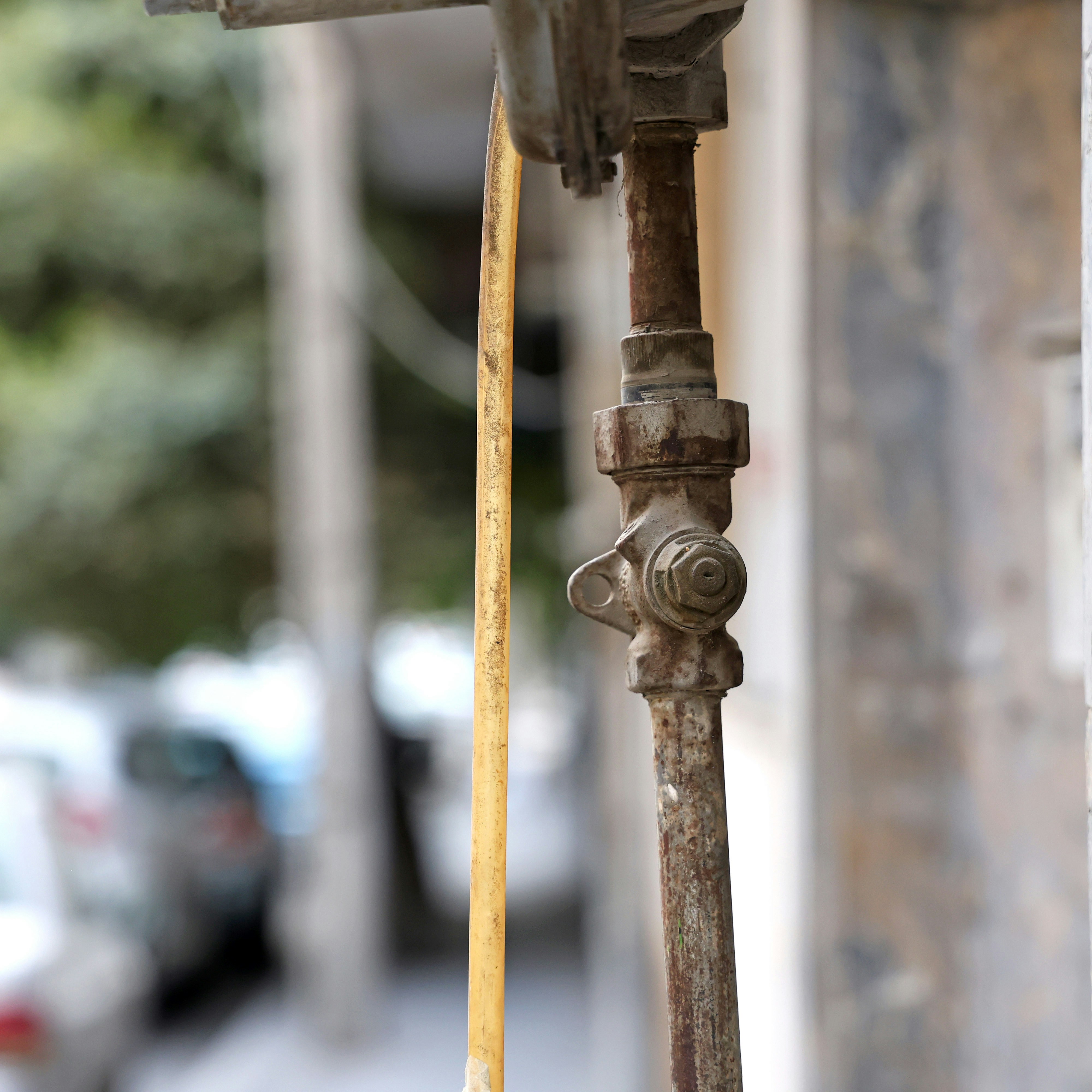 Close-up of an outdoor plumbing pipe with a valve and hose attached