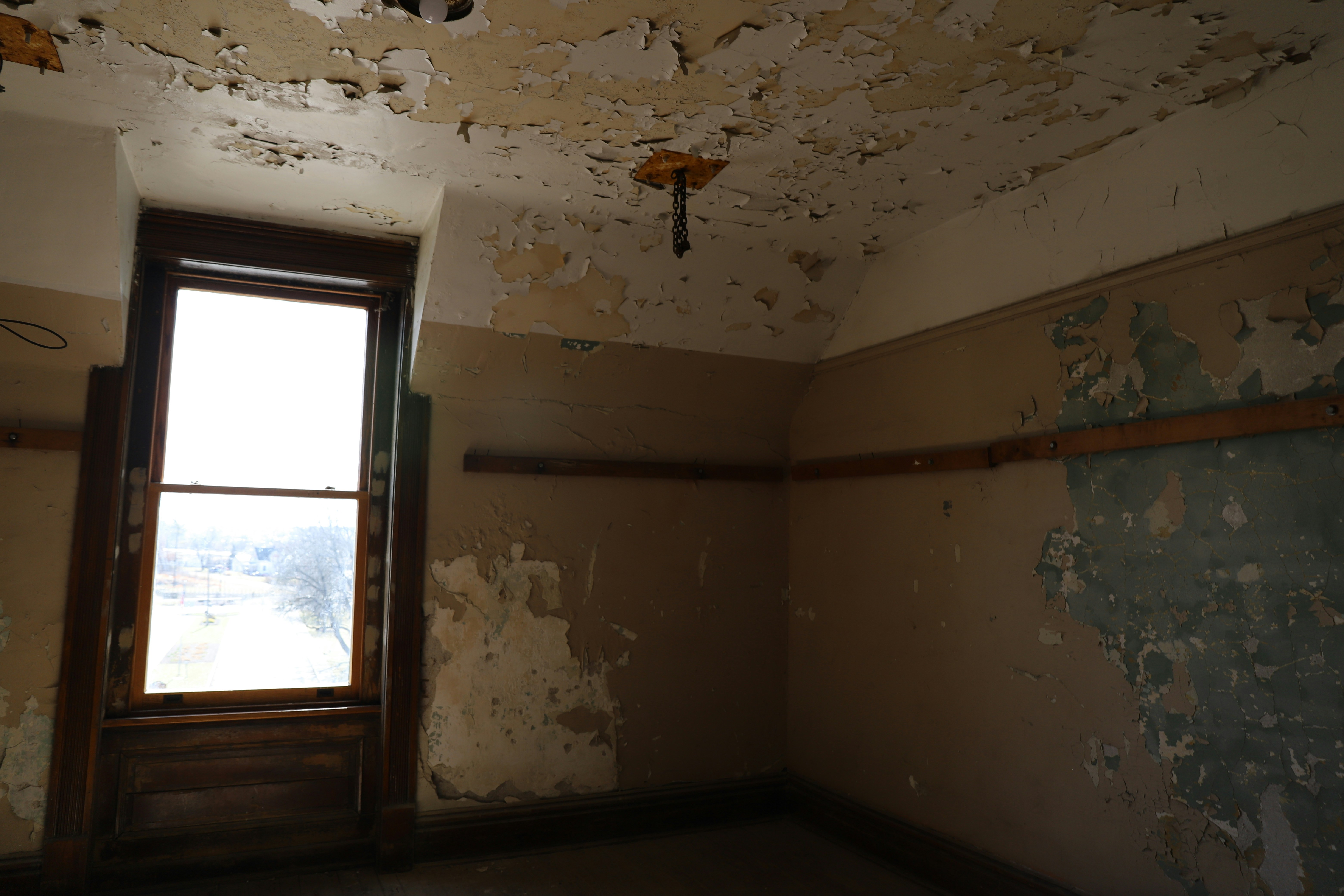 Room with peeling paint and a single window