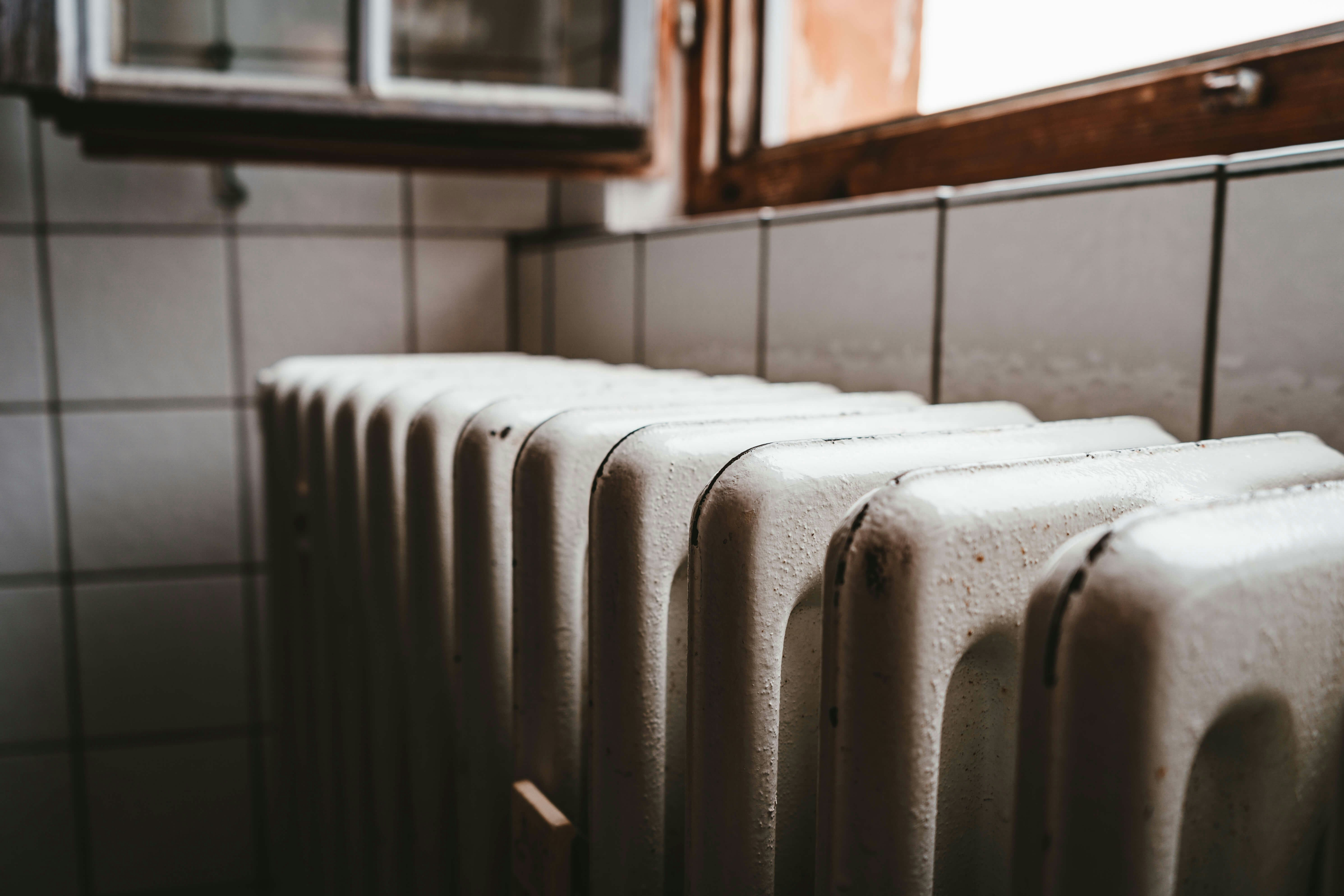 Close-up of a white radiator in a tiled room near a window