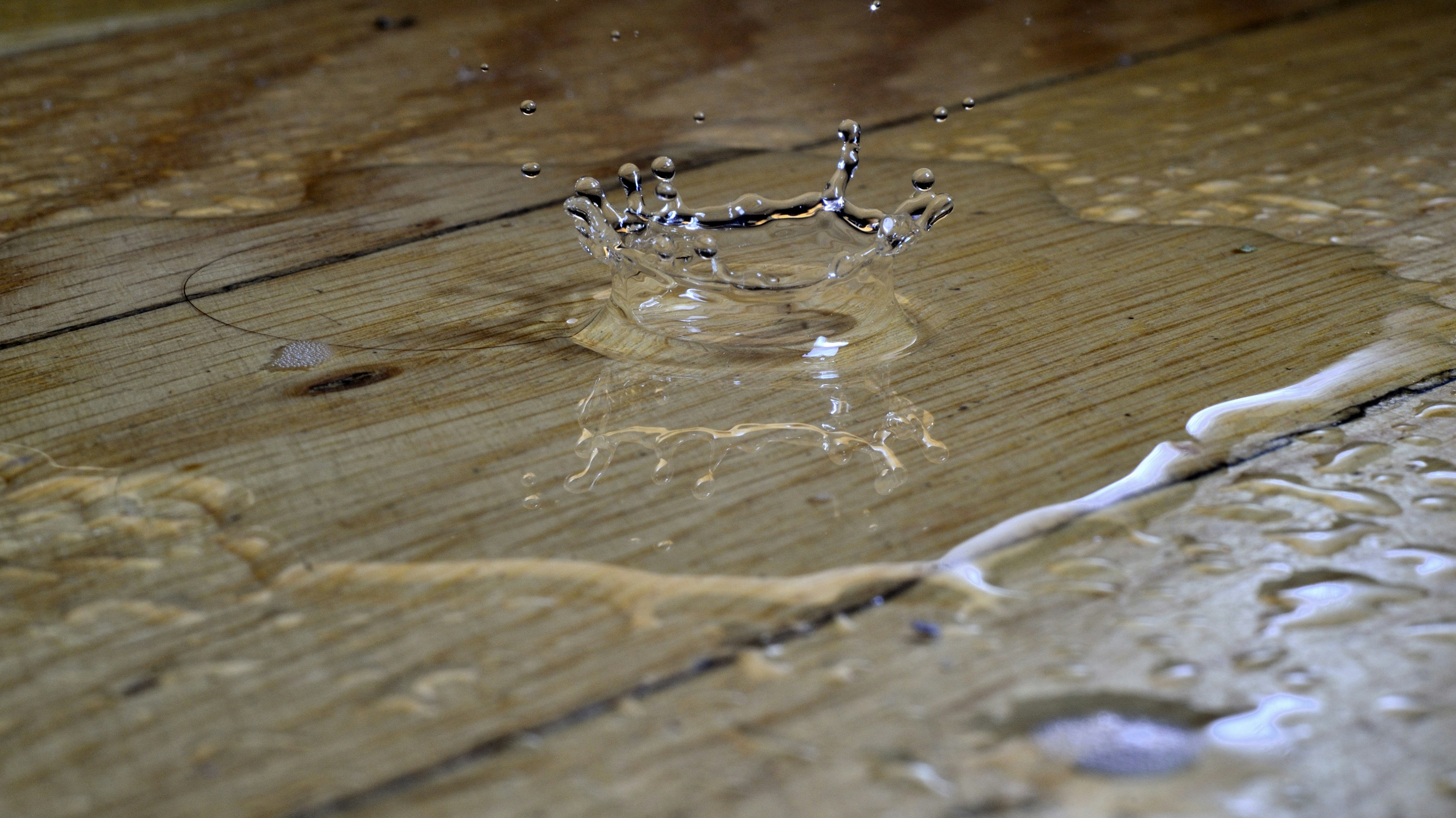 Close-up of a water droplet splashing on a wooden surface