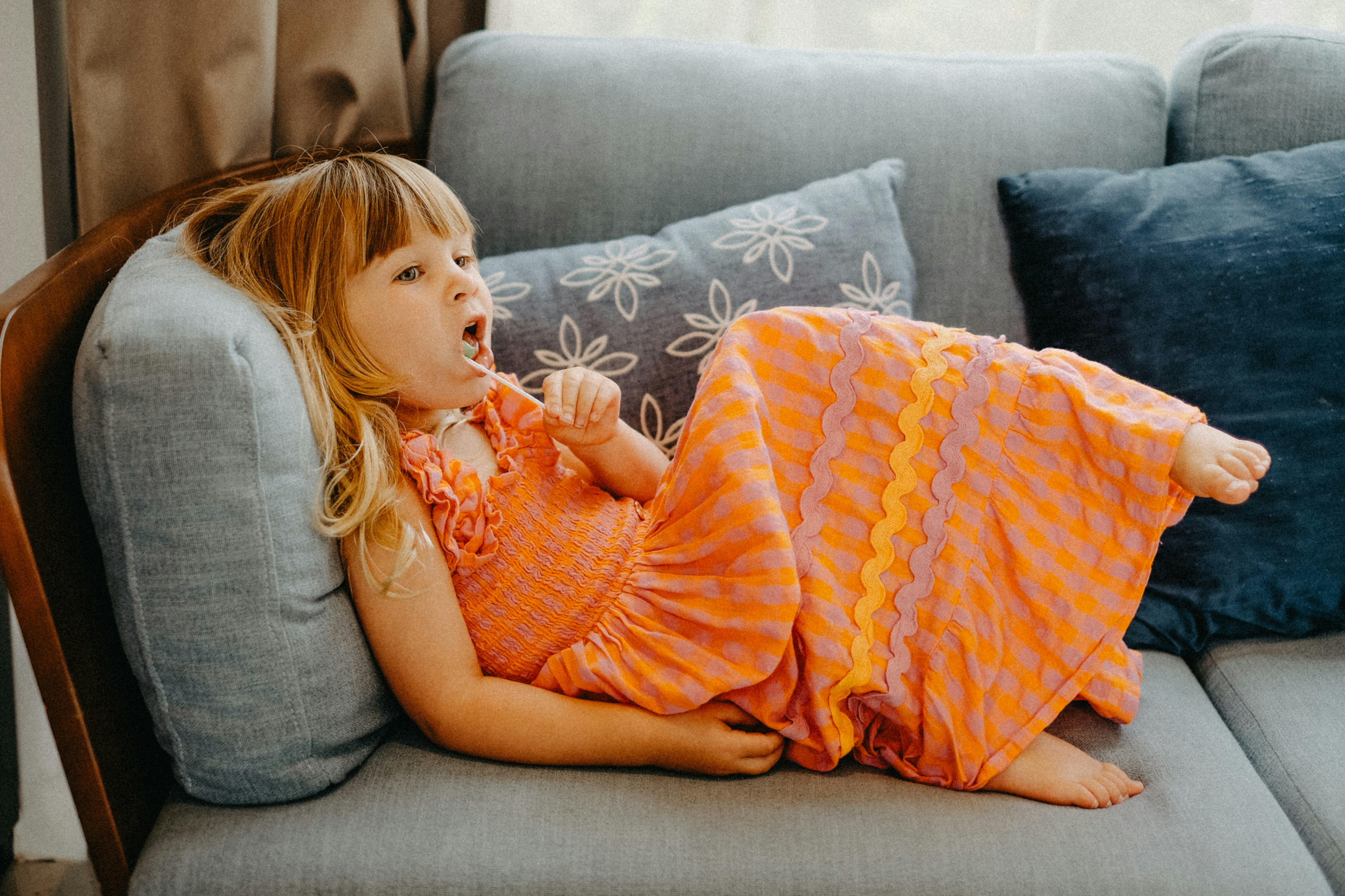 Young girl in a colorful dress lounging on a couch